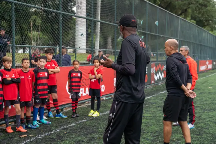 Treinador do Flamengo Escola de Futebol passando orientações para os atletas à beira do campo